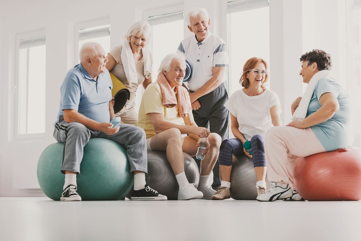 grupo de personas de avanzada edad sentadas sobre pelotas de goma