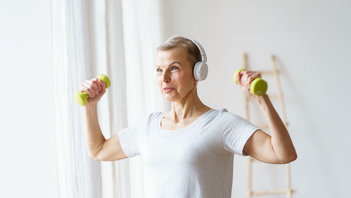 mujer de avanzada edad escuchano músic mientras levanta unas pesas